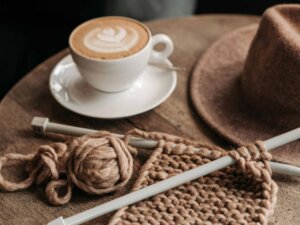 Eine Tasse Kaffee steht neben einer Stricknadel