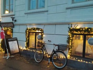 Ein Fahrrad lehnt an einer Hauswand, die Fenster sind mit Lichterketten geschmückt.