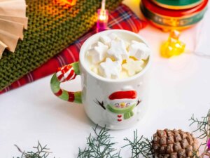 Eine Tasse mit einem Schneemann-Motiv ist mit Kakao und Marshmallows gefüllt.